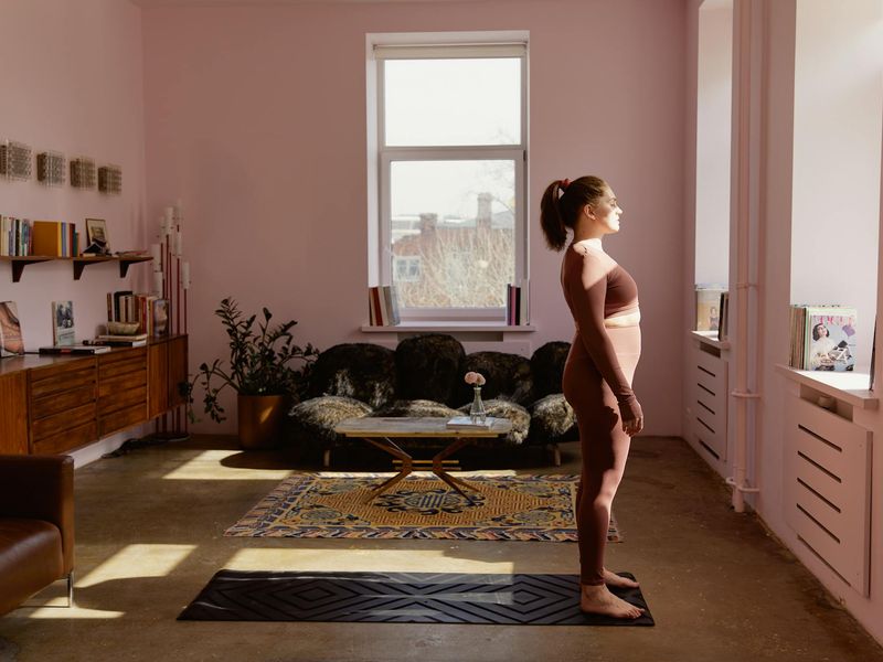 A person in a calm yoga pose inside a minimalist room with natural light.